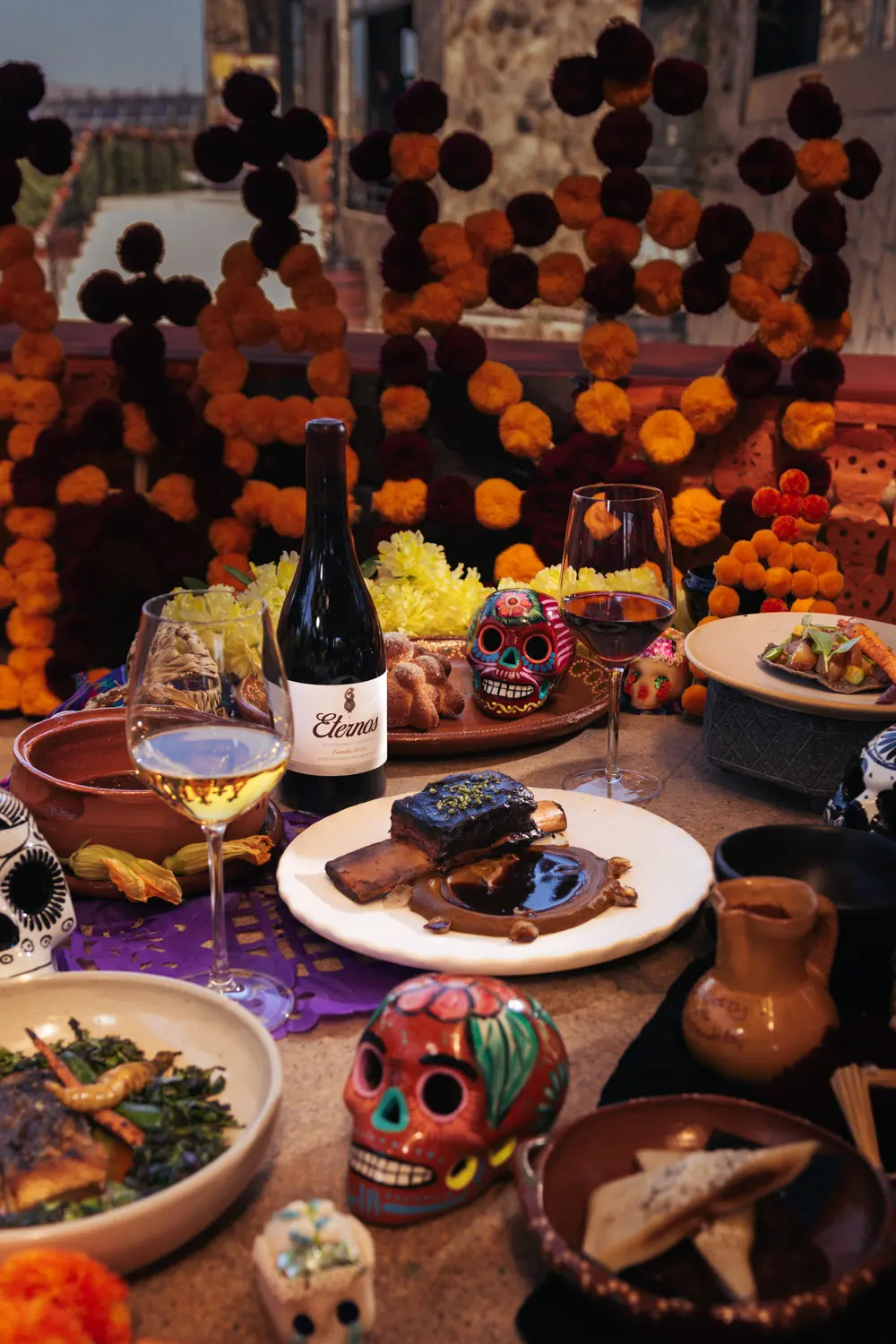 Mesa con altar de cempasúchil, vino Eternos y los platillos de la cena